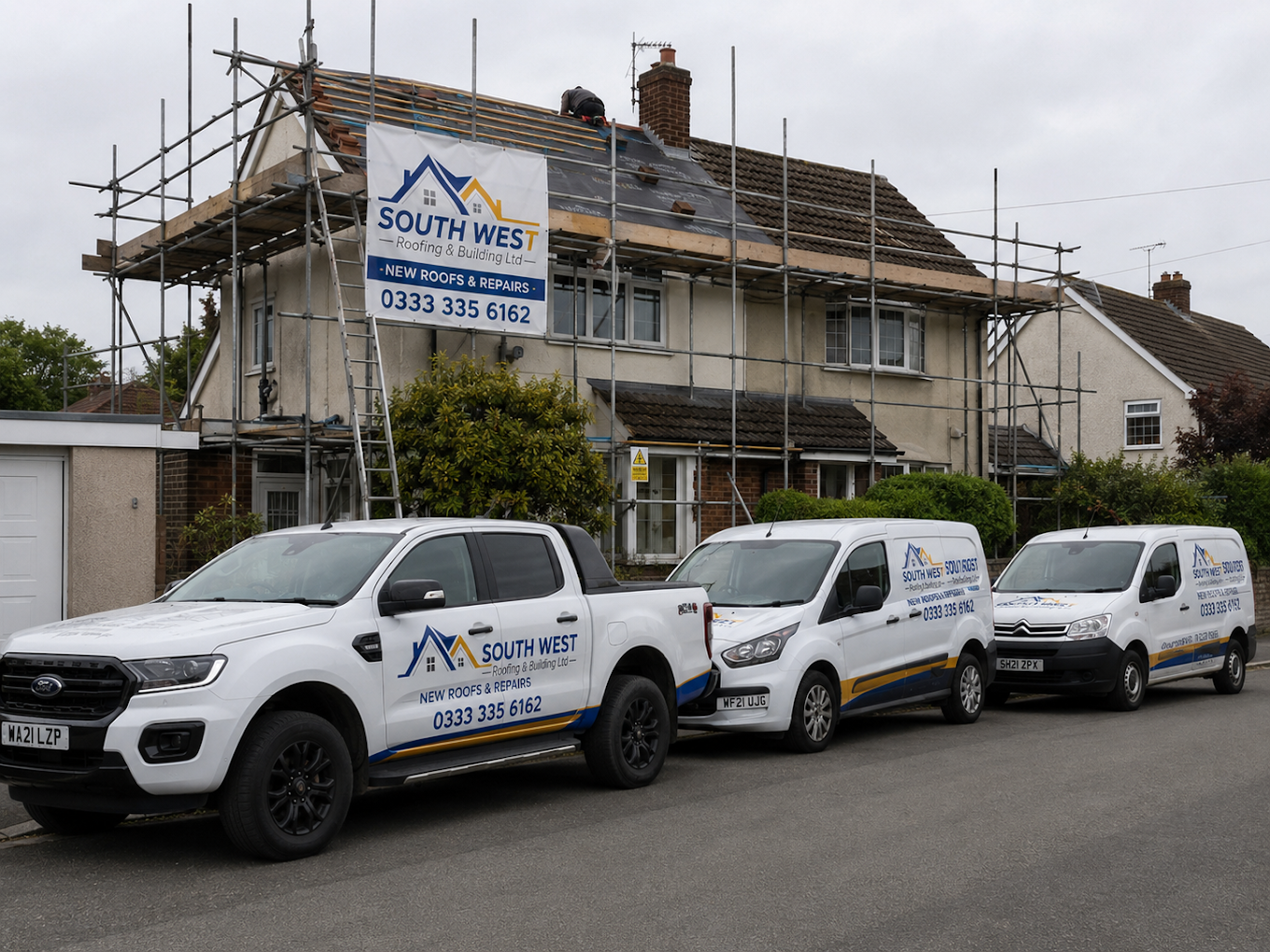 Scaffolded home with the South West Roofing vehicle fleet parked outside